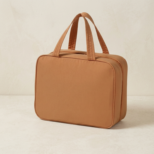 Brown travel toiletry bag on a pale stone surface with an ivory background